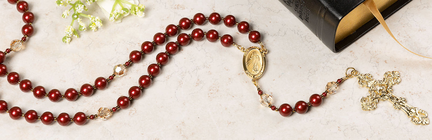 Photo of red rosary on white table with a black bible